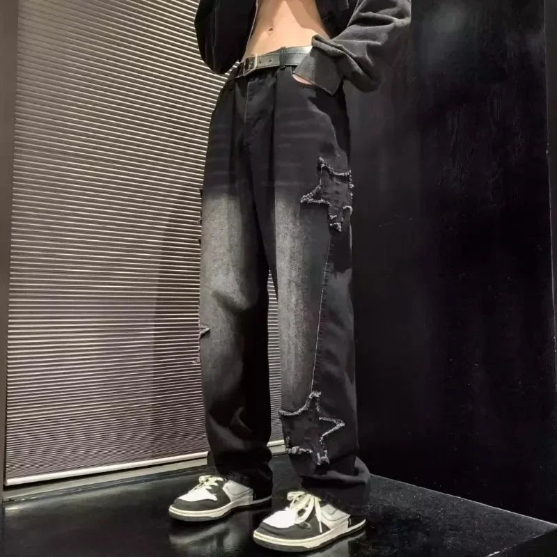 Black ripped jeans with star patches, paired with white sneakers and black belt for casual streetwear style
