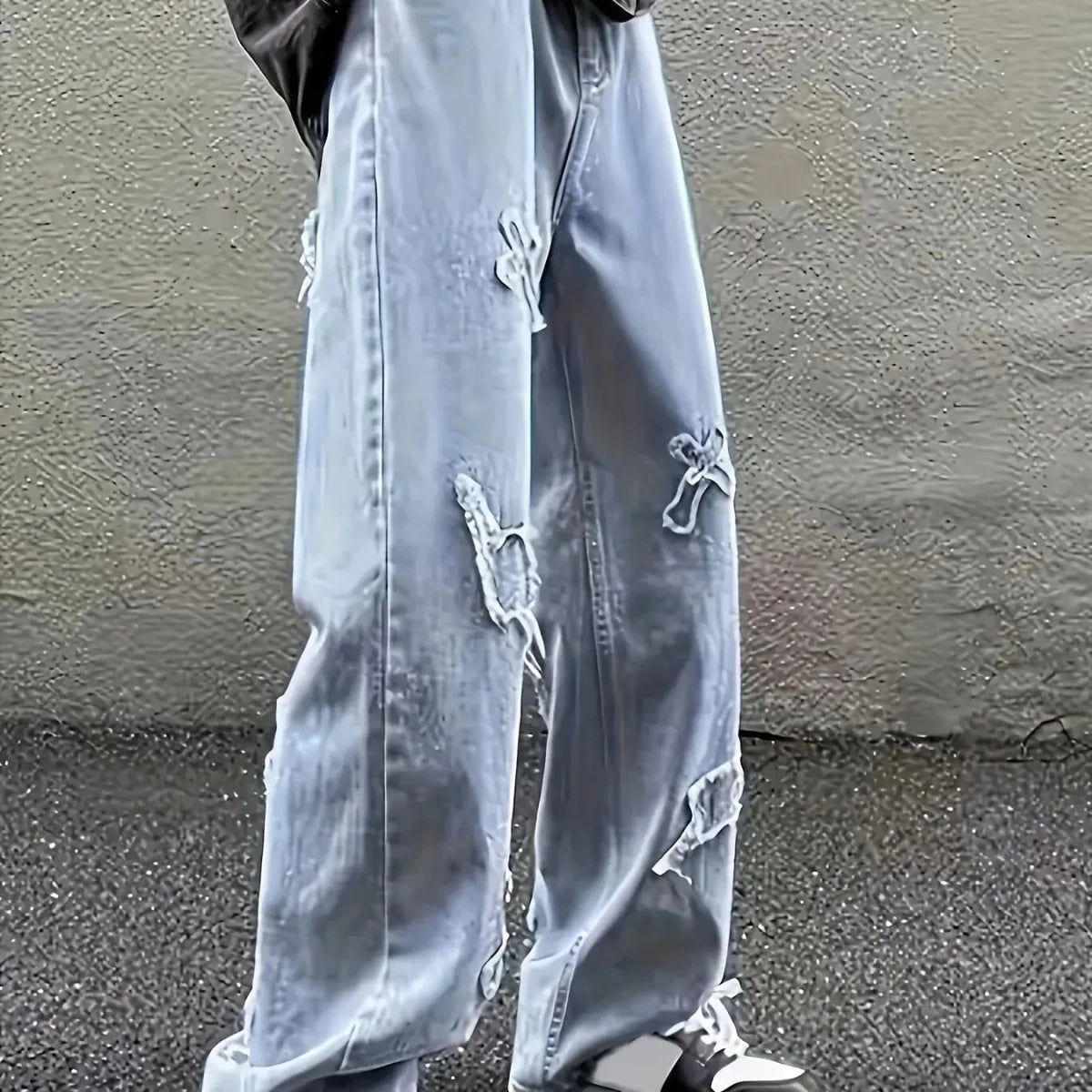 Distressed wide-leg jeans with ripped details, paired with sneakers for modern streetwear style